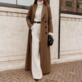 Woman wearing brown long trench coat over cream sweater and pants