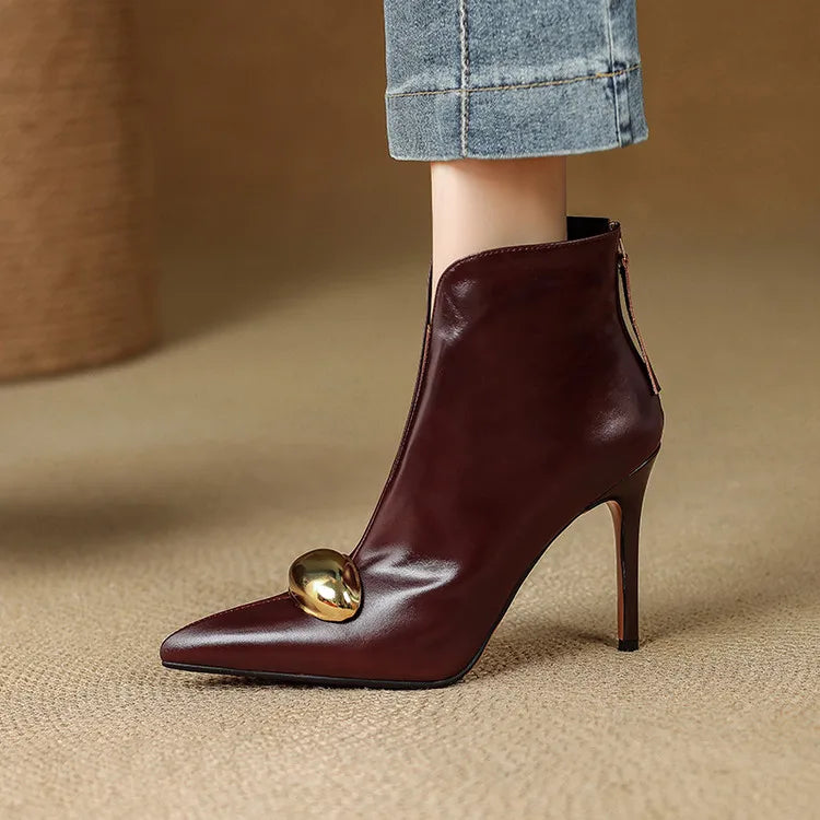 Model wearing burgundy ankle boot with gold ornament, front view
